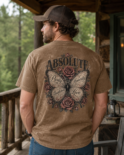 A man wearing a brown t-shirt with a large butterfly and rose graphic on the back, standing on a rustic wooden porch.
