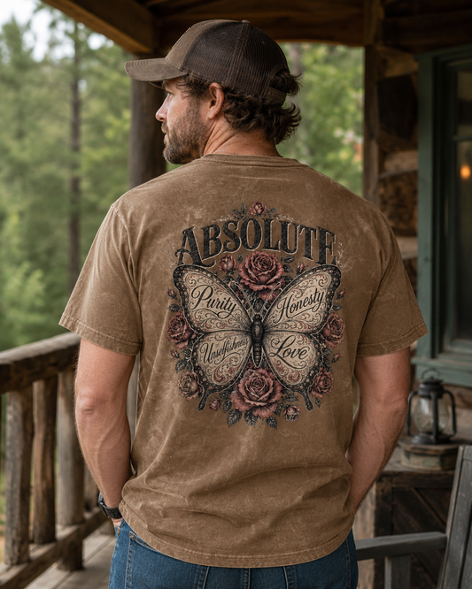 A man wearing a brown t-shirt with a large butterfly and rose graphic on the back, standing on a rustic wooden porch.